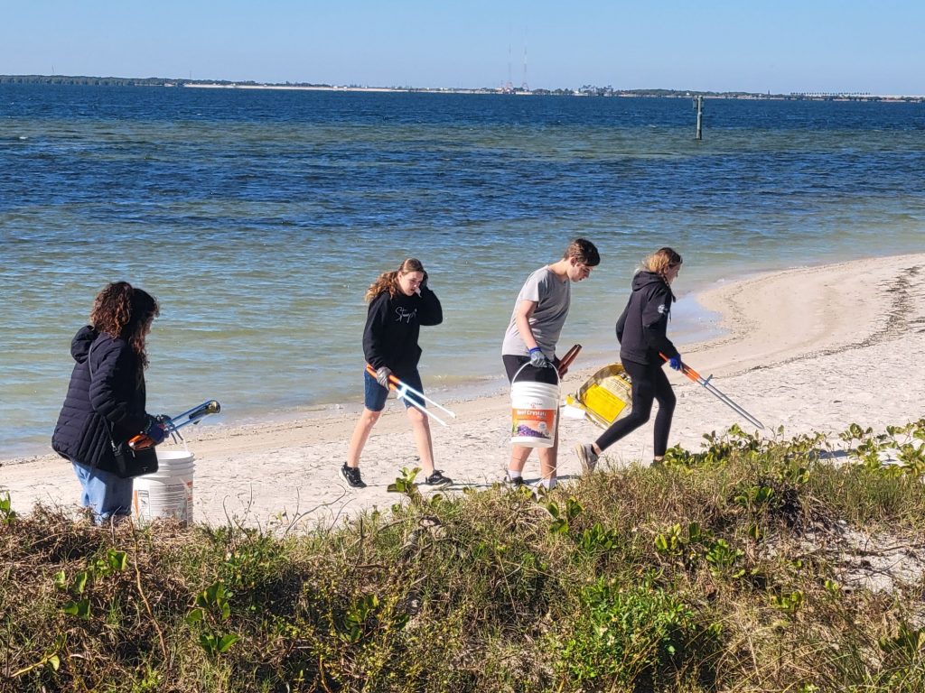 youth picking up marine debris off the beach